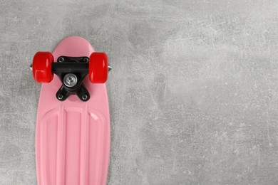 Photo of Pink skateboard on grey stone background, top view. Space for text
