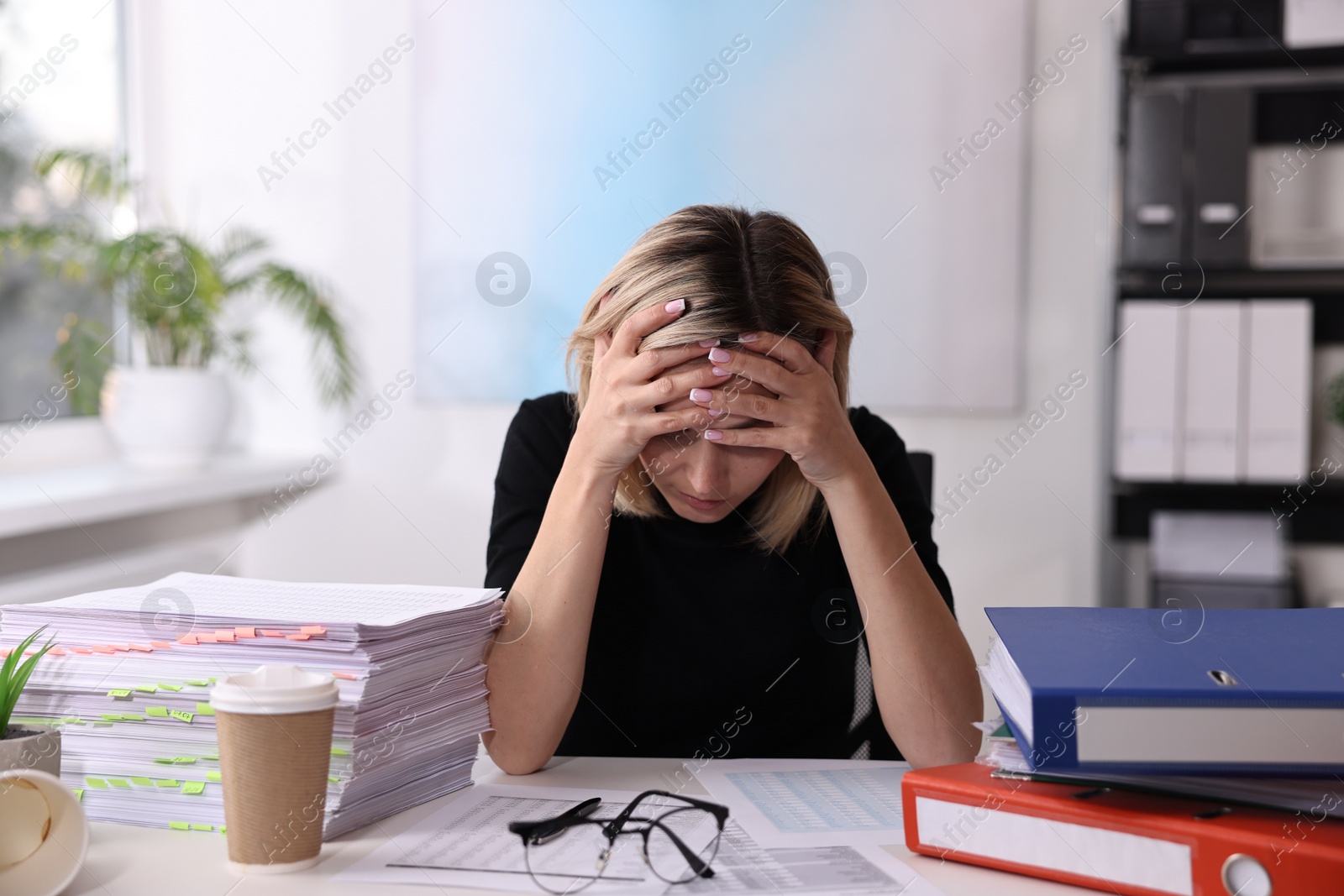 Photo of Overwhelmed woman sitting at table in office