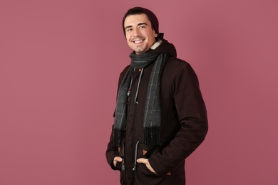 Photo of Portrait of happy young man in warm clothing on color background. Ready for winter vacation