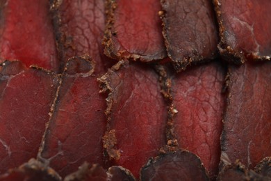 Photo of Delicious dry-cured beef basturma slices as background, top view