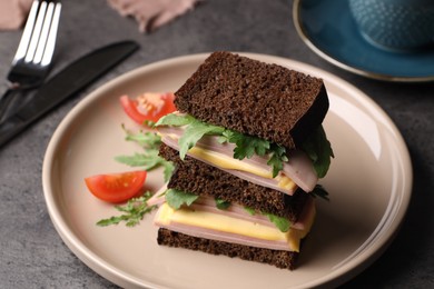 Photo of Delicious sandwiches with boiled sausage, tomato, cheese and arugula on grey table, closeup