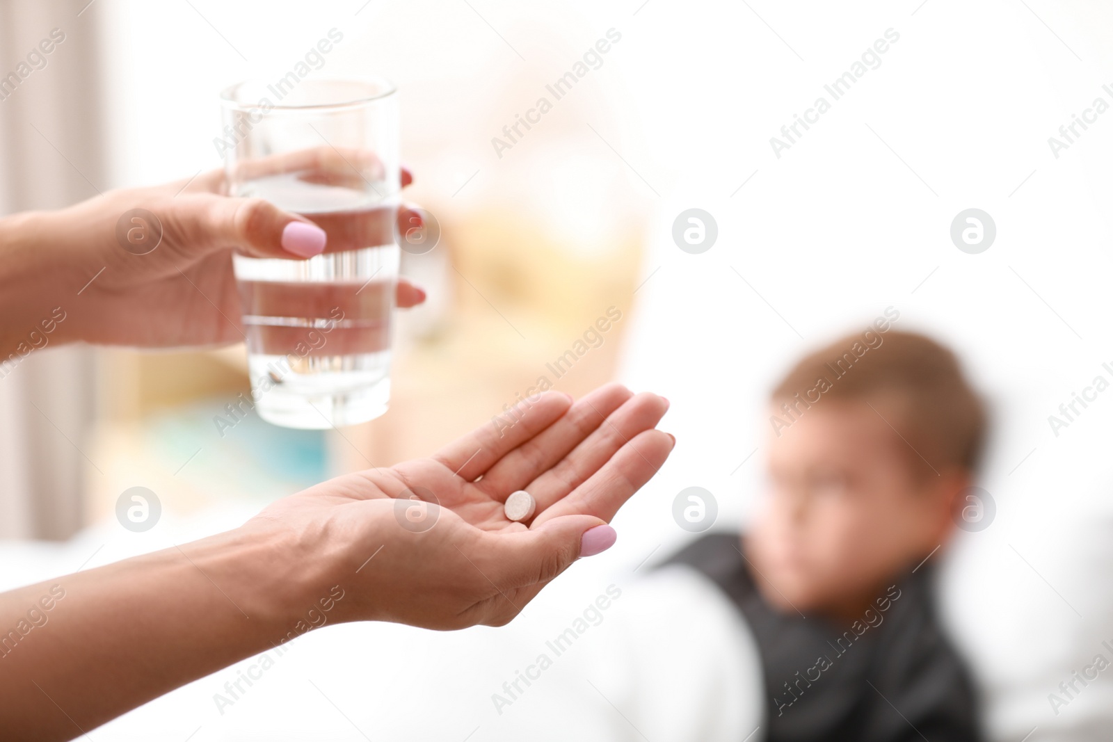 Photo of Mother with pill and water and her sick son in bed, closeup. Space for text