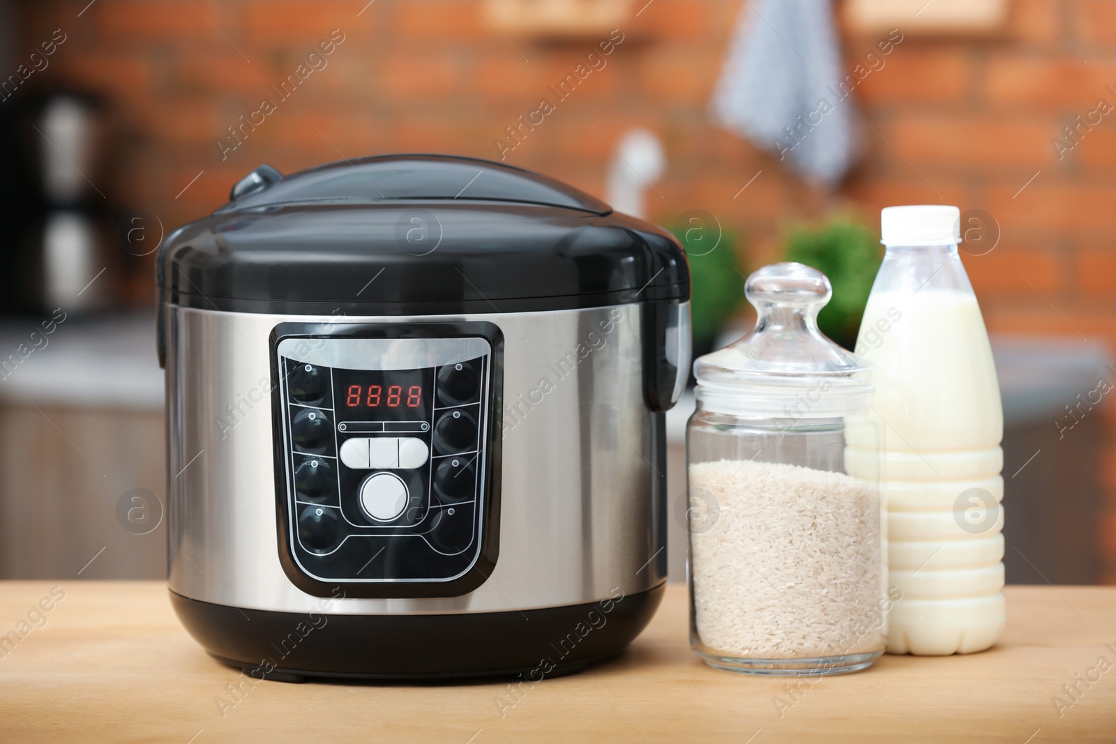 Photo of Modern electric multi cooker, rice and milk on table in kitchen