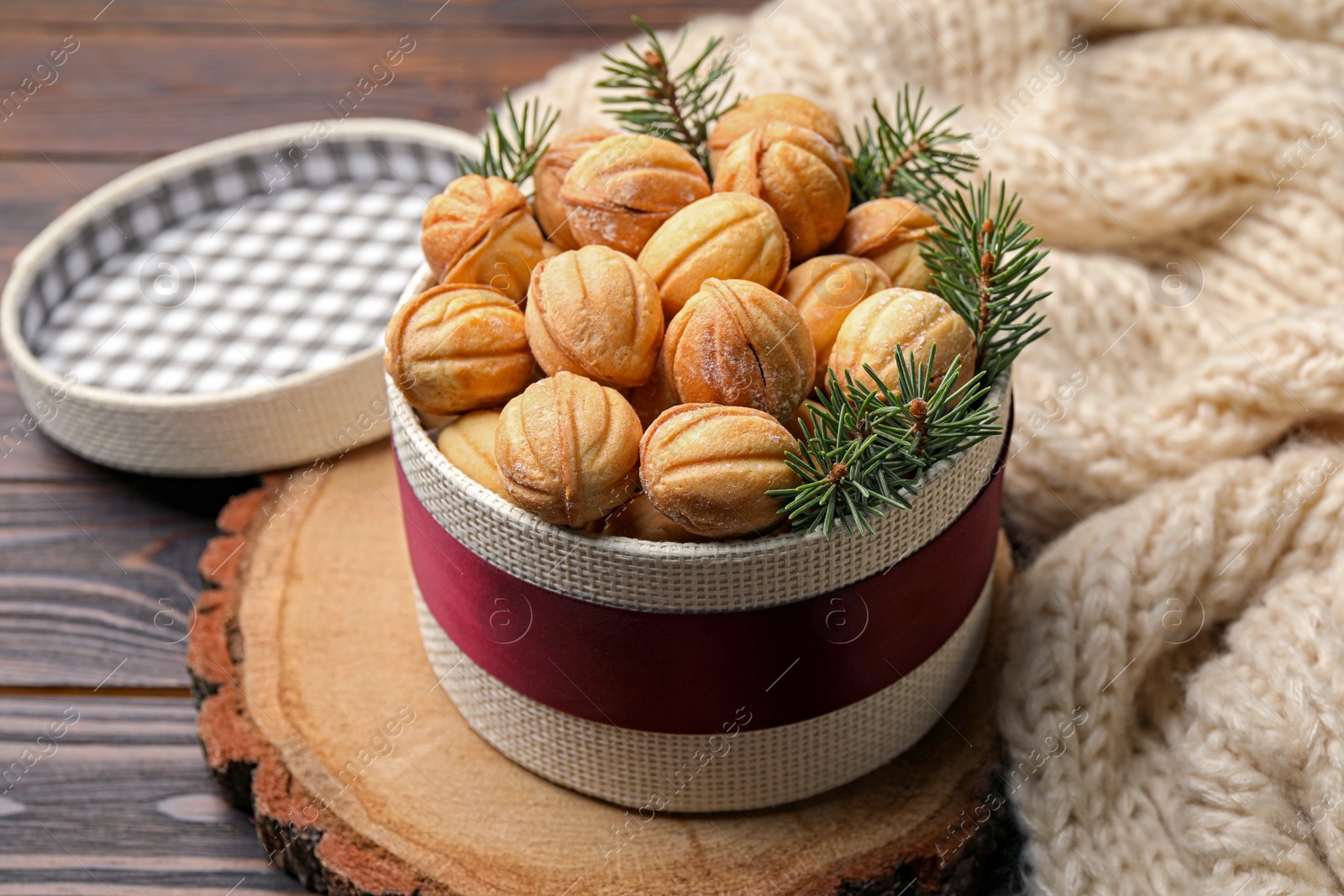 Photo of Bowl of delicious nut shaped cookies and fir tree branches on wooden table