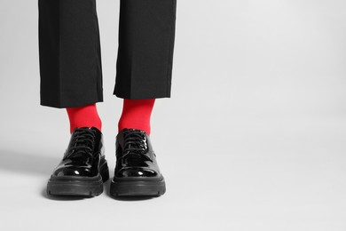 Photo of Woman in pants, shoes and stylish red socks on light grey background, closeup. Space for text