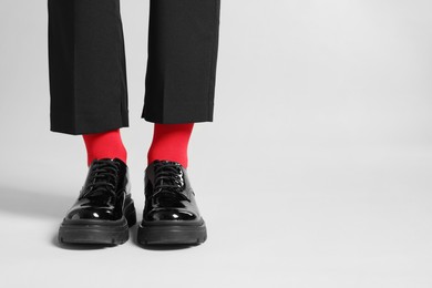 Woman in pants, shoes and stylish red socks on light grey background, closeup. Space for text