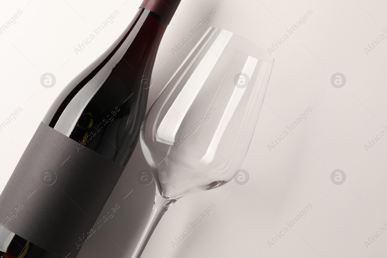 Photo of Bottle of tasty red wine and glass on white background, flat lay. Space for text