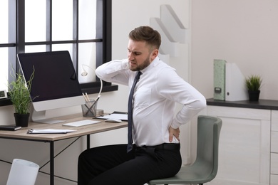 Photo of Businessman suffering from back pain at workplace