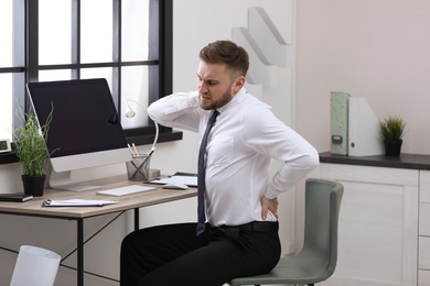 Businessman suffering from back pain at workplace