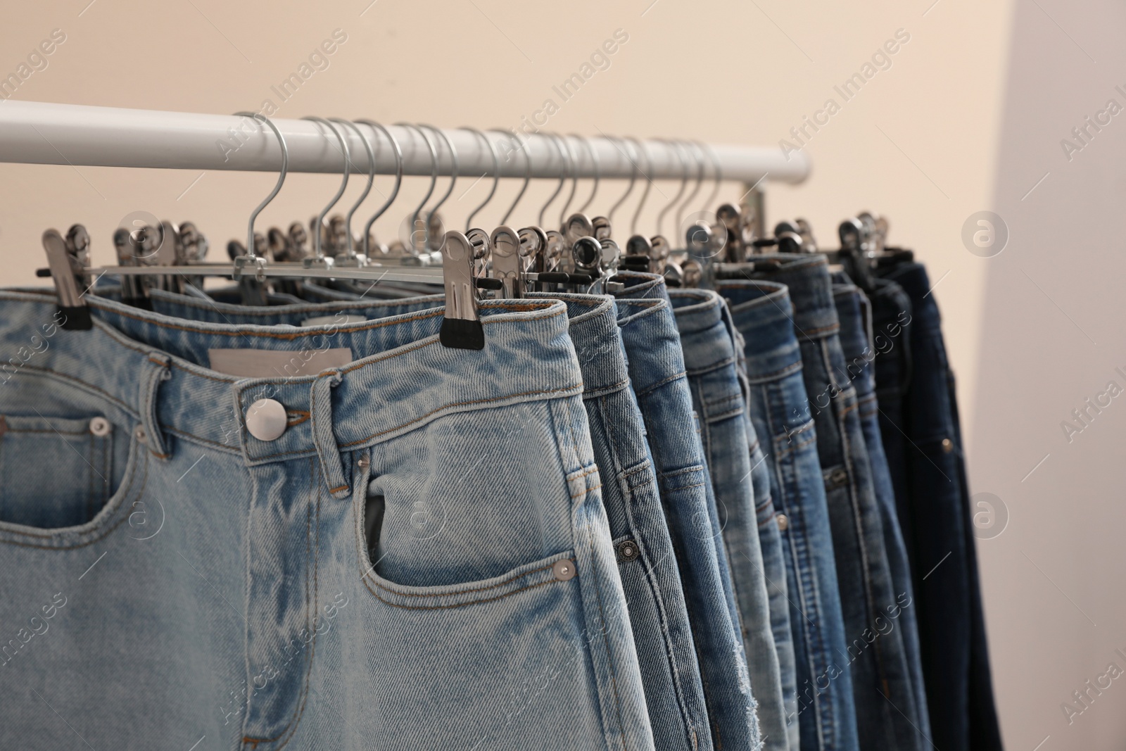 Photo of Rack with stylish jeans on color background, closeup