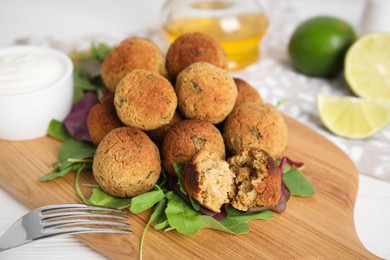 Photo of Delicious falafel balls with herbs on white table, closeup