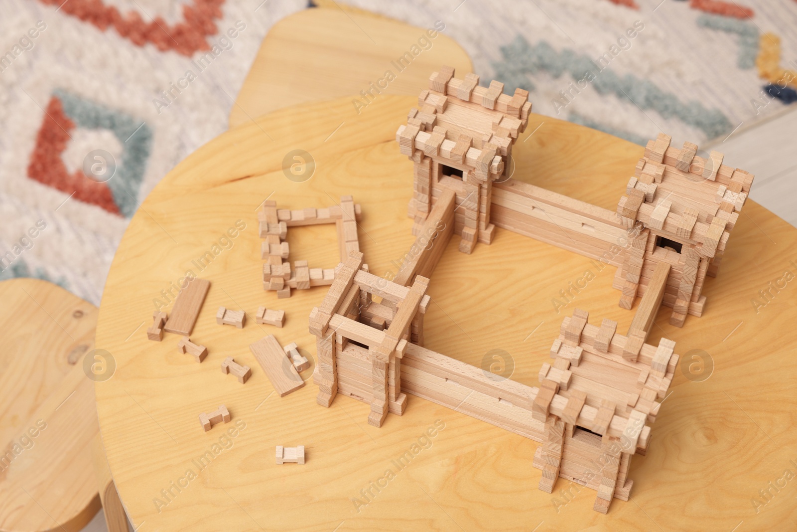 Photo of Wooden fortress and building blocks on table indoors. Children's toy