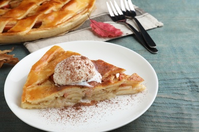 Slice of traditional apple pie with ice cream served on blue wooden table, closeup