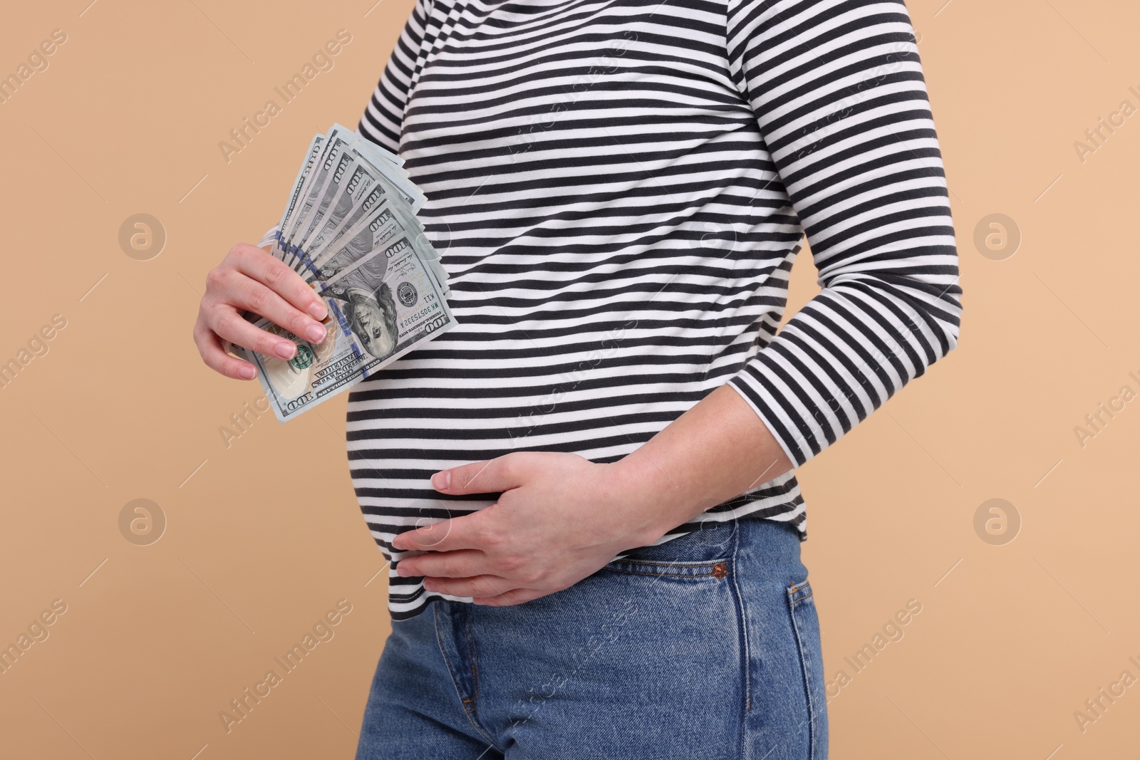 Photo of Surrogate mother. Pregnant woman with dollar banknotes on beige background, closeup