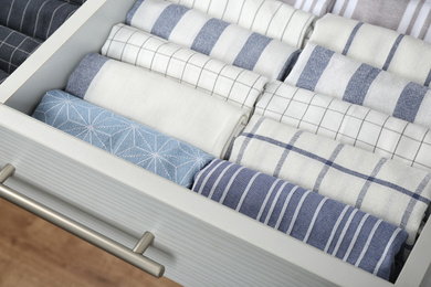 Photo of Open drawer with folded towels, closeup. Order in kitchen