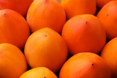 Pile of delicious ripe juicy persimmons as background, closeup