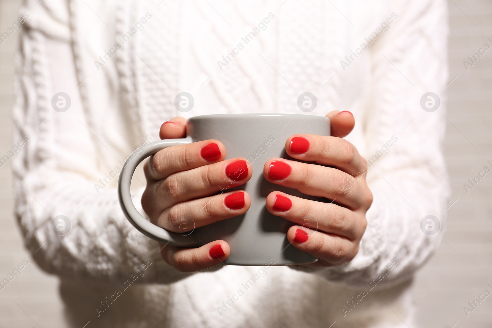 Photo of Woman with red manicure holding cup, closeup. Nail polish trends