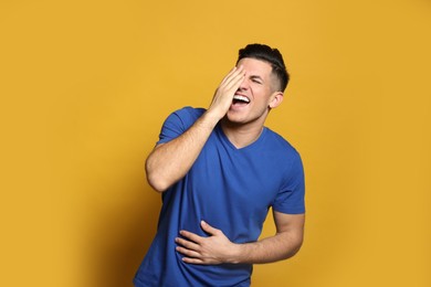 Handsome man laughing on yellow background. Funny joke