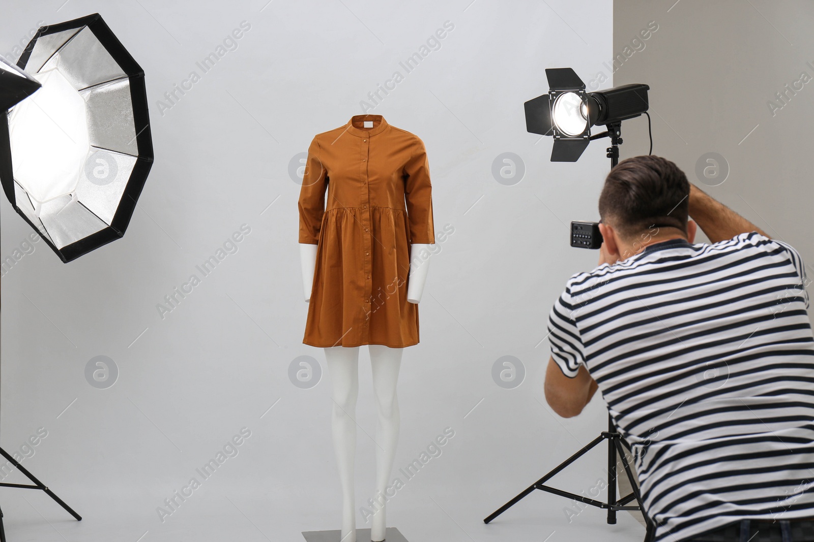 Photo of Professional photographer taking picture of ghost mannequin with stylish clothes in modern photo 
 studio