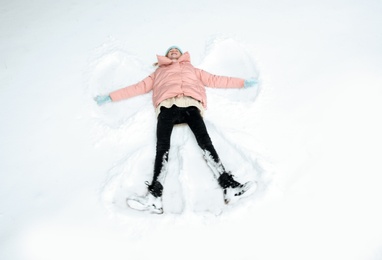 Teenage girl making snow angel on winter day