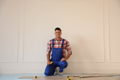 Photo of Professional worker installing new parquet flooring indoors