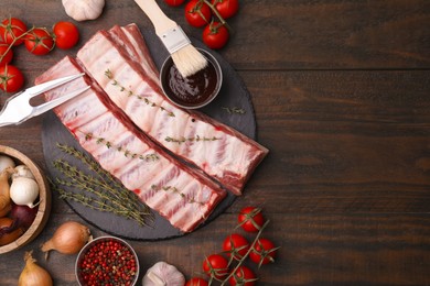Photo of Flat lay composition with raw pork ribs and sauce on wooden table. Space for text