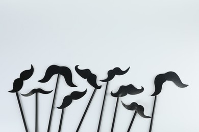 Photo of Fake paper mustaches party props on light background, flat lay. Space for text