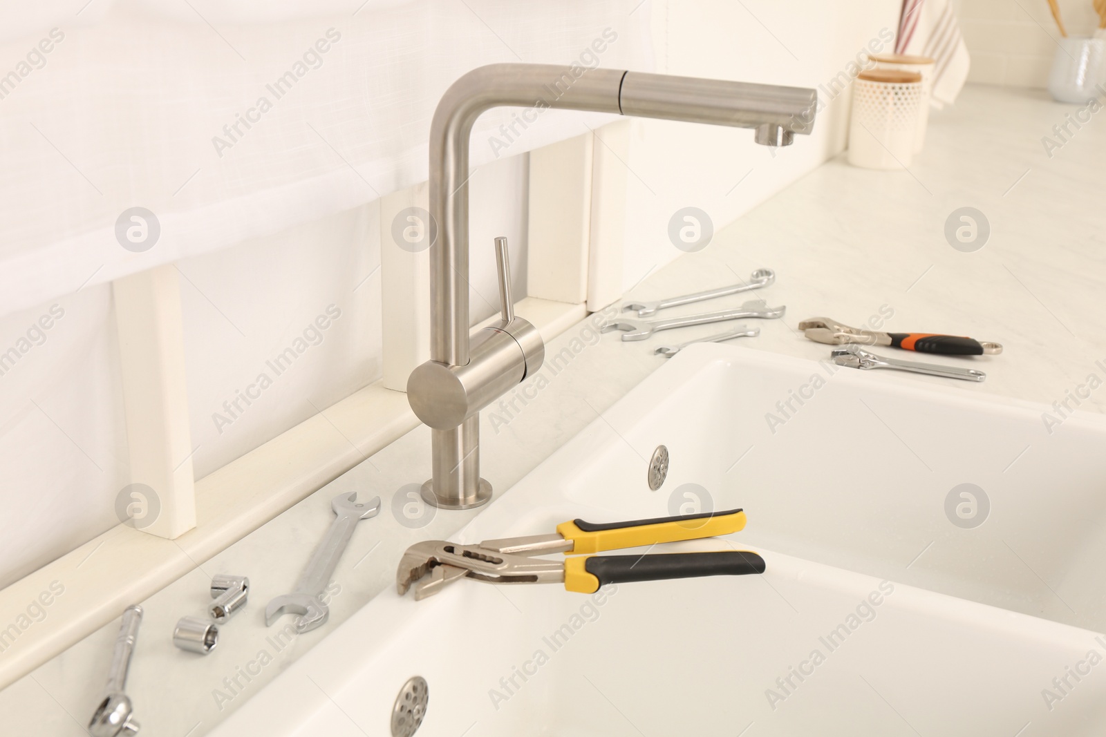 Photo of Installed water tap and plumber's tools near sink on countertop in kitchen