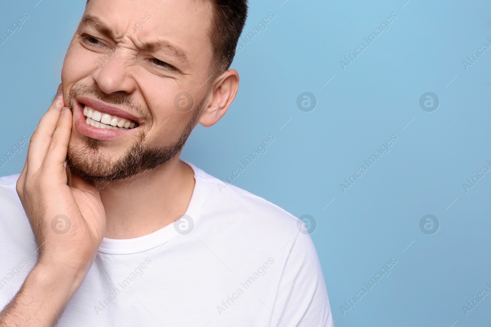 Photo of Young man suffering from toothache on grey background