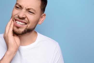 Young man suffering from toothache on grey background