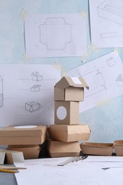 Photo of Creating packaging design. Drawings, boxes and stationery on table, closeup