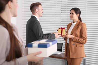 Photo of Woman presenting gift to her colleague in office