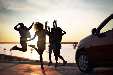 Image of Friends having fun near car on street. Silhouettespeople at sunset