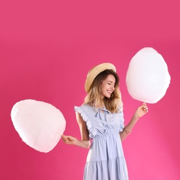 Photo of Happy young woman with cotton candies on pink background