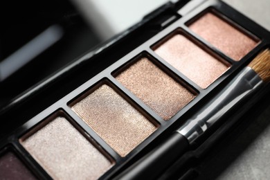 Beautiful eye shadow palette with brush on grey textured table, closeup