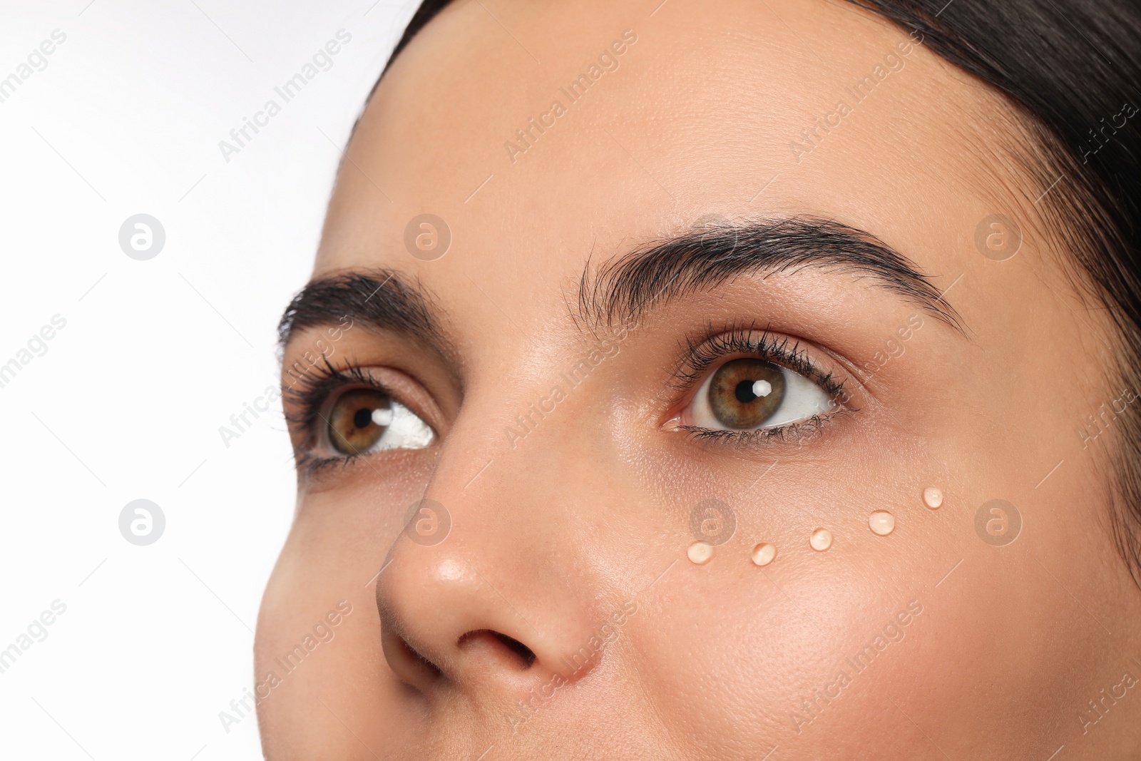 Photo of Closeup view of young woman with gel on skin under eye against white background