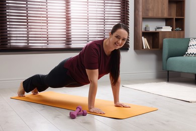Photo of Overweight woman doing plank exercise at home