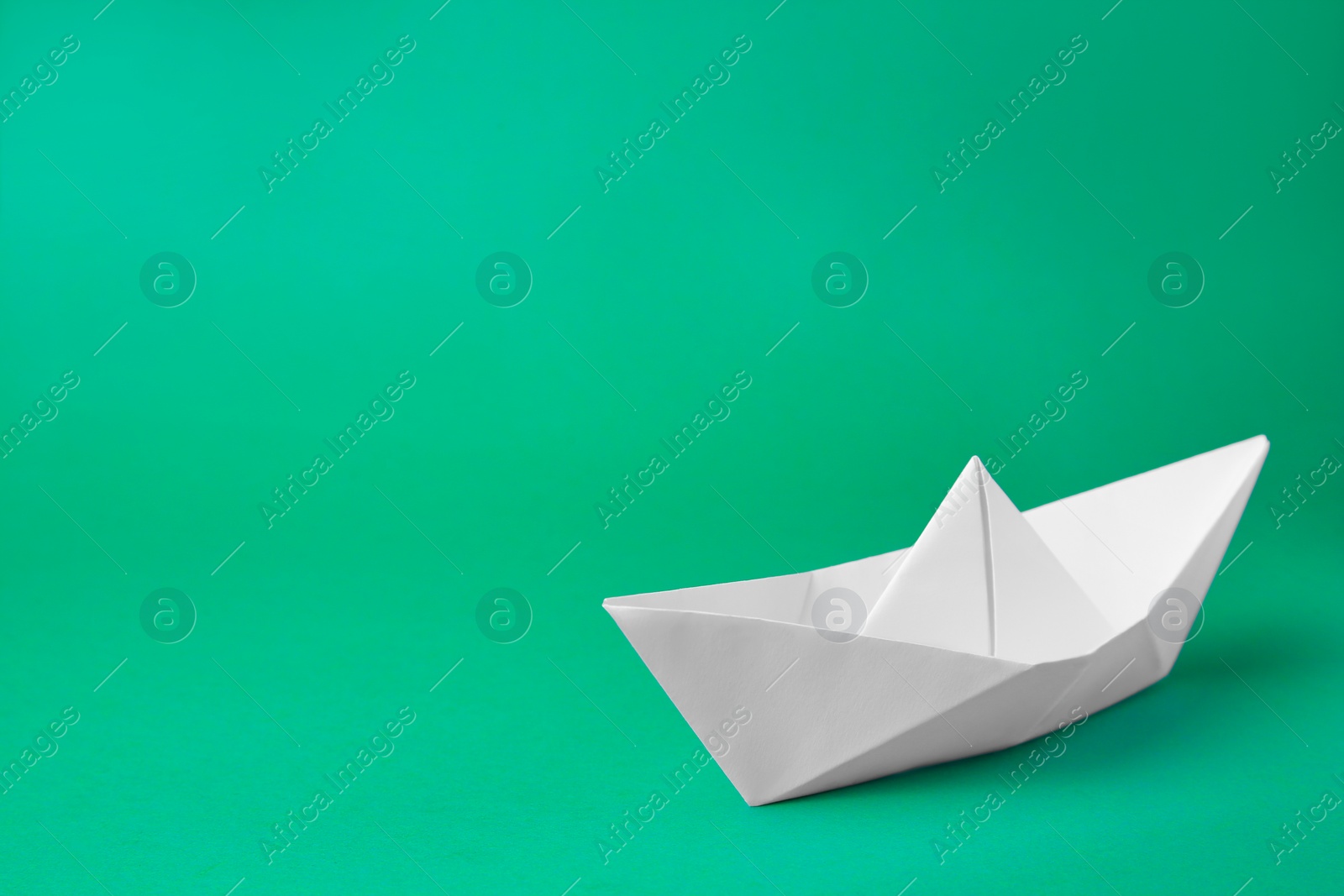 Photo of Origami art. Paper boat on green background, space for text