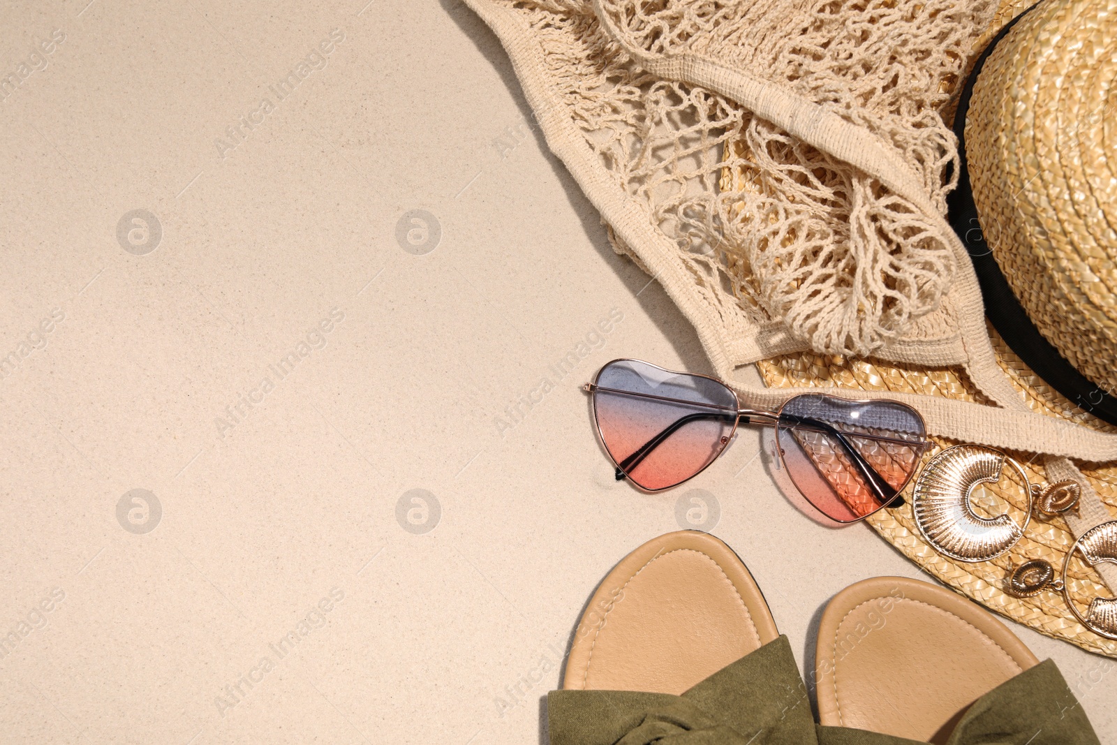 Photo of Flat lay composition with stylish sunglasses and other fashionable accessories on sand. Space for text