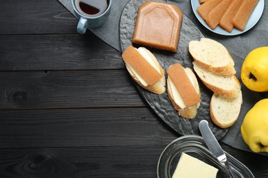 Photo of Tasty sandwiches with quince paste served on black wooden table, top view. Space for text