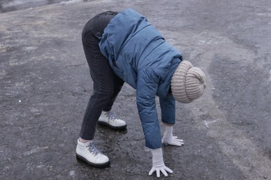 Photo of Young woman having difficulties with moving on icy road outdoors