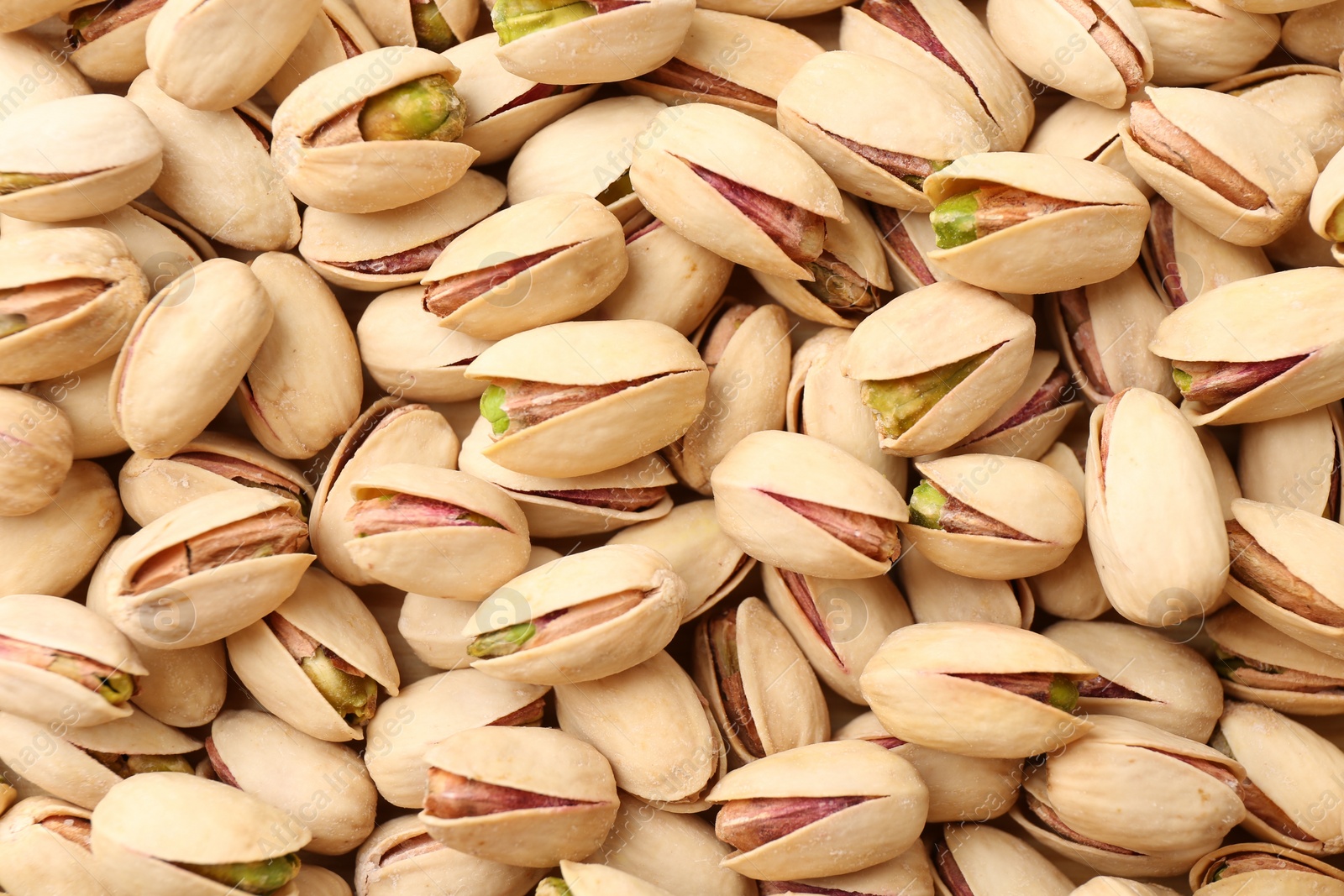 Photo of Tasty unpeeled pistachios as background, top view