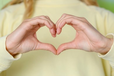 Photo of Young woman making heart with hands, closeup