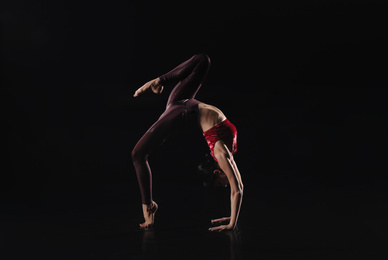 Photo of Young woman performing acrobatic element on stage indoors. Space for text