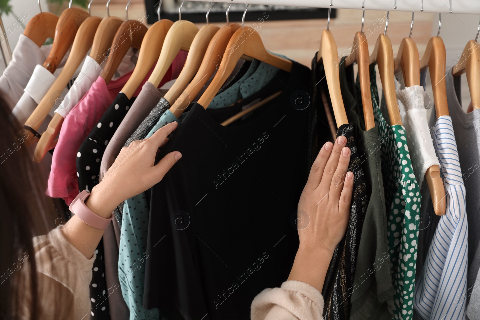 Photo of Woman choosing clothes from wardrobe rack, closeup