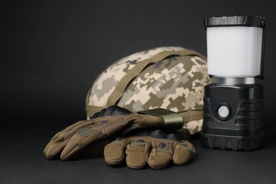 Photo of Tactical gloves, helmet and camping lantern on black background. Military training equipment