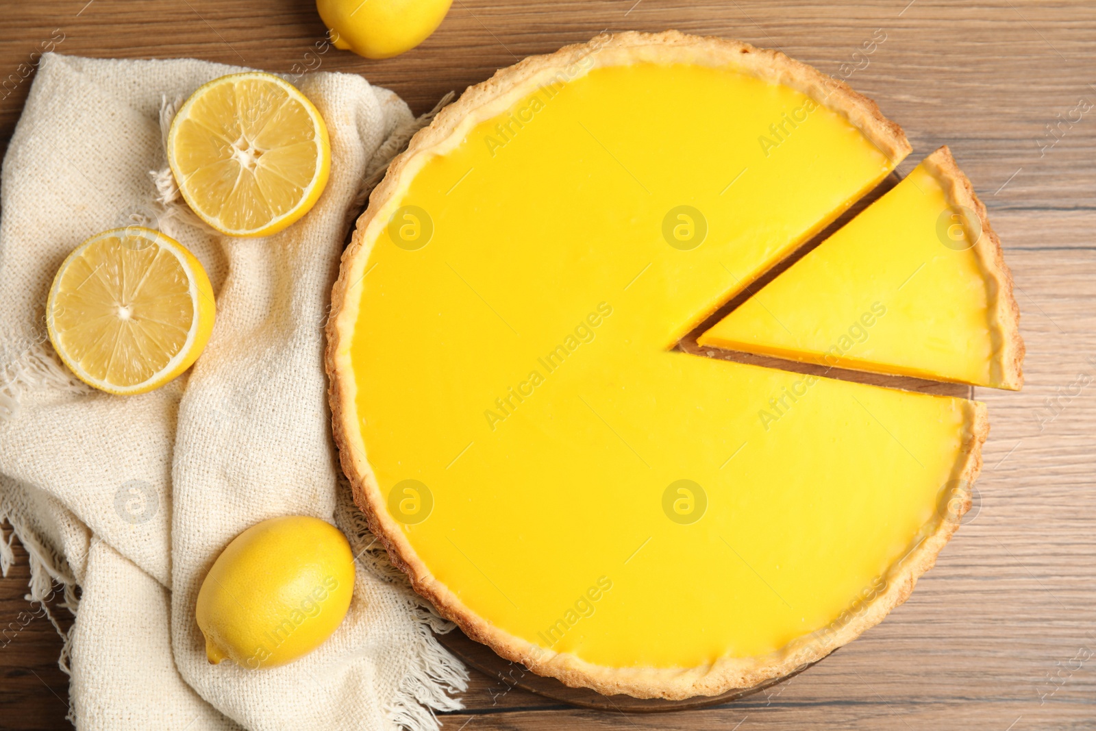 Photo of Delicious homemade lemon pie and fruits on wooden table, flat lay