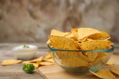 Photo of Bowl of Mexican nacho chips on wooden table. Space for text