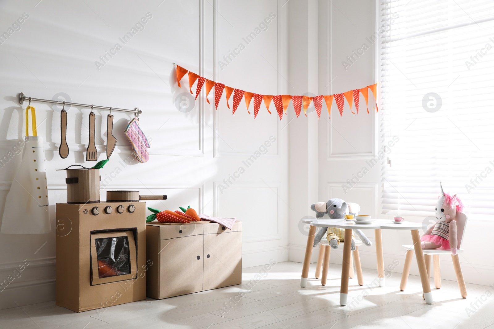 Photo of Toy cardboard kitchen with stove and utensils at home