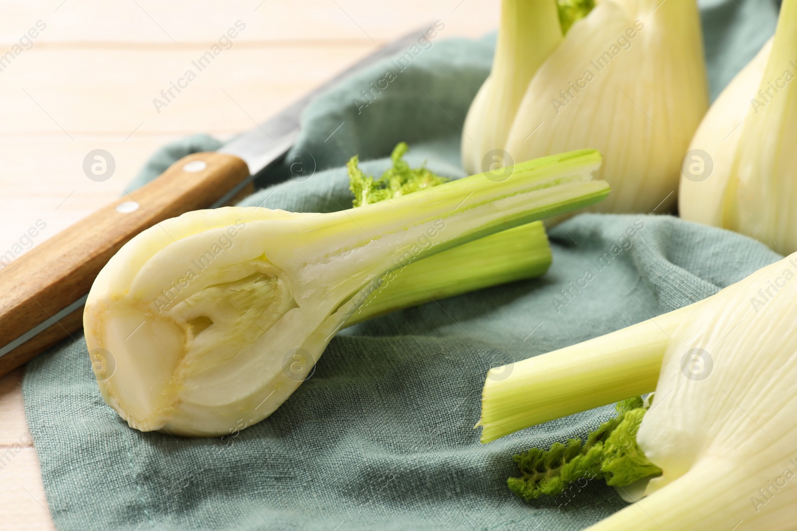 Photo of Fresh raw fennel bulbs and knife on table, closeup